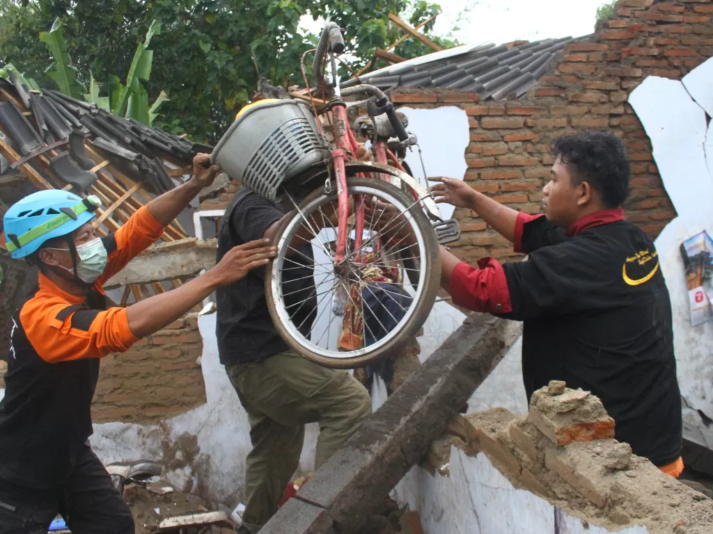 Relawan membantu warga menyelamatkan barang di sebuah rumah yang hancur akibat gempa di Majangtengah, Malang, Jawa Timur, Minggu (11/4/2021). (ANTARA FOTO/Ari Bowo Sucipto)