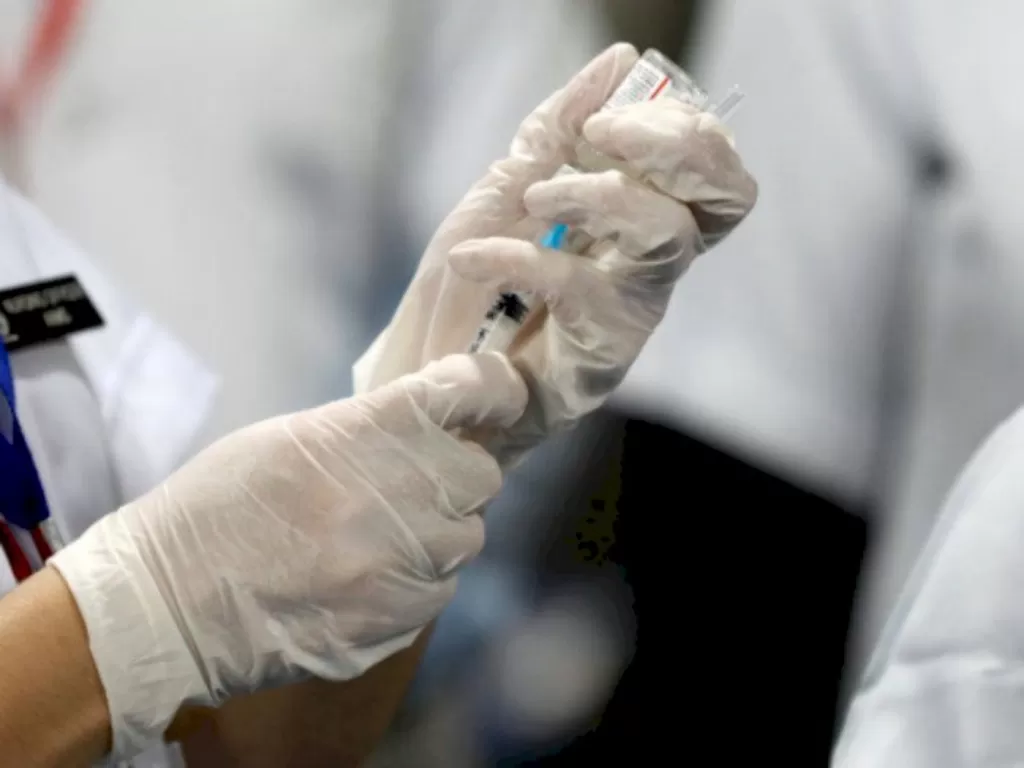 Seorang petugas kesehatan mengisi jarum suntik dengan dosis vaksin COVID-19. (REUTERS/Adnan Abidi)