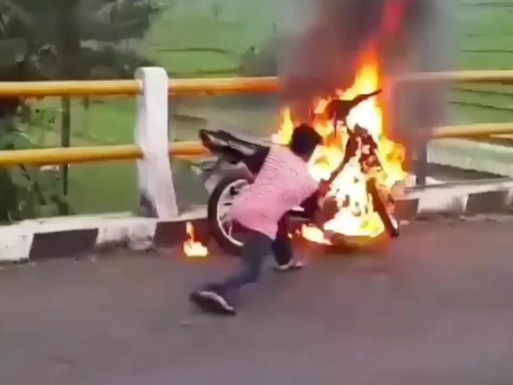 Pemuda padamkan motornya yang terbakar. (Tangkapan layar)