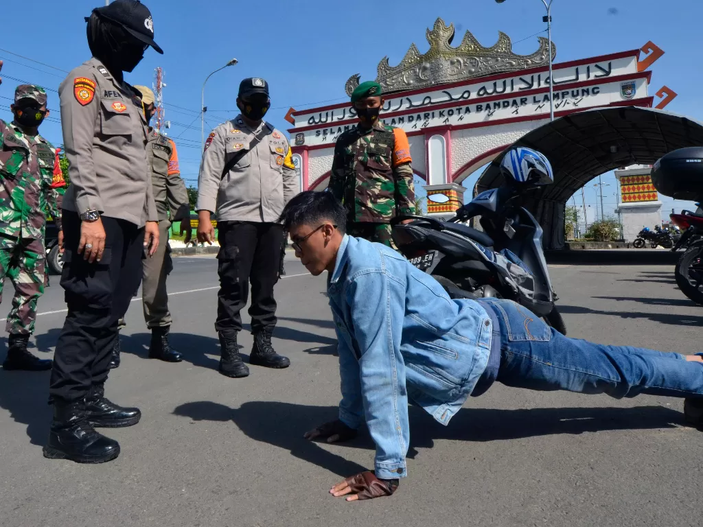 Petugas gabungan Satgas COVID-19 Kota Bandar Lampung memberikan hukuman kepada pengendara motor yang tidak mengenakan masker (ANTARA FOTO/Ardiansyah)