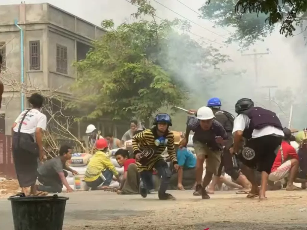 Pengunjuk rasa berlindung saat bentrok dengan pasukan keamanan di Monywa, Myanmar, Minggu (21/3/2021). (REUTERS/aww)
