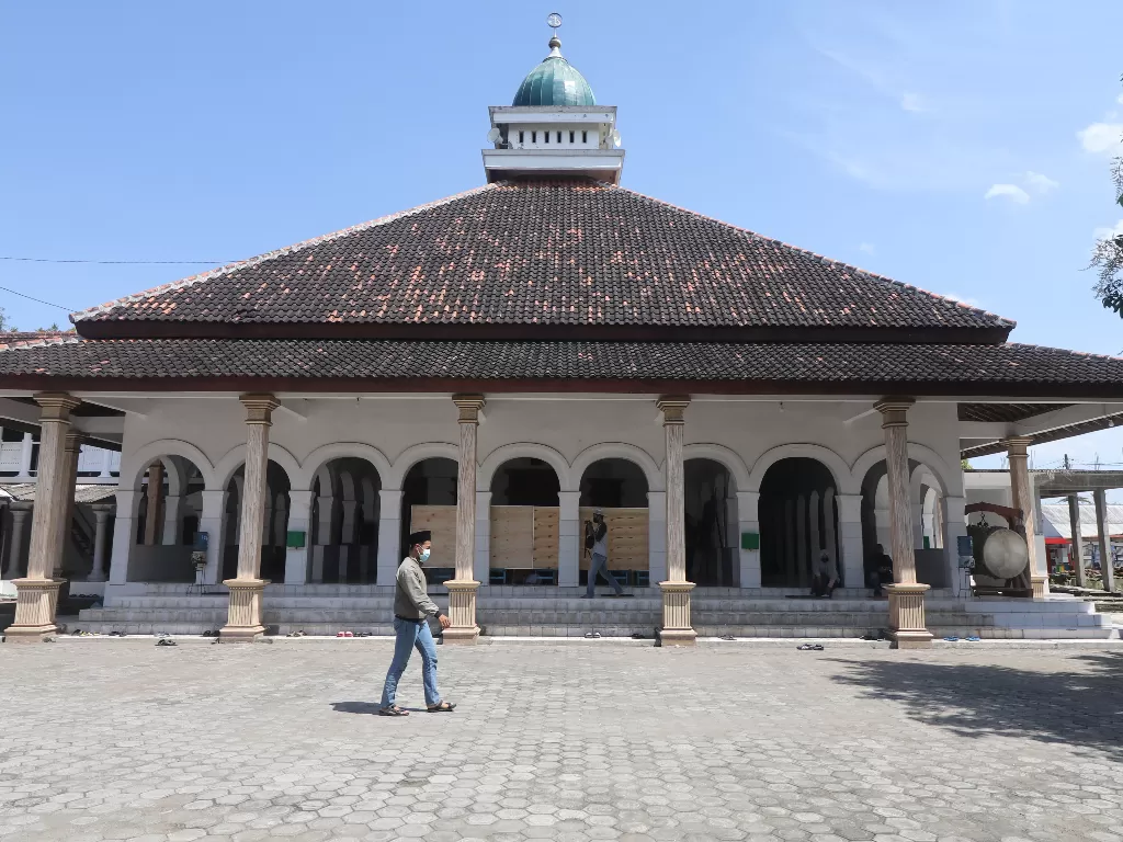 Pengunjung melintas di depan masjid kawasan pondok pesantren (ponpes) Kapurejo, Kediri, Jawa Timur, Sabtu (17/4/2021).  (ANTARA FOTO/Prasetia Fauzani/foc.).