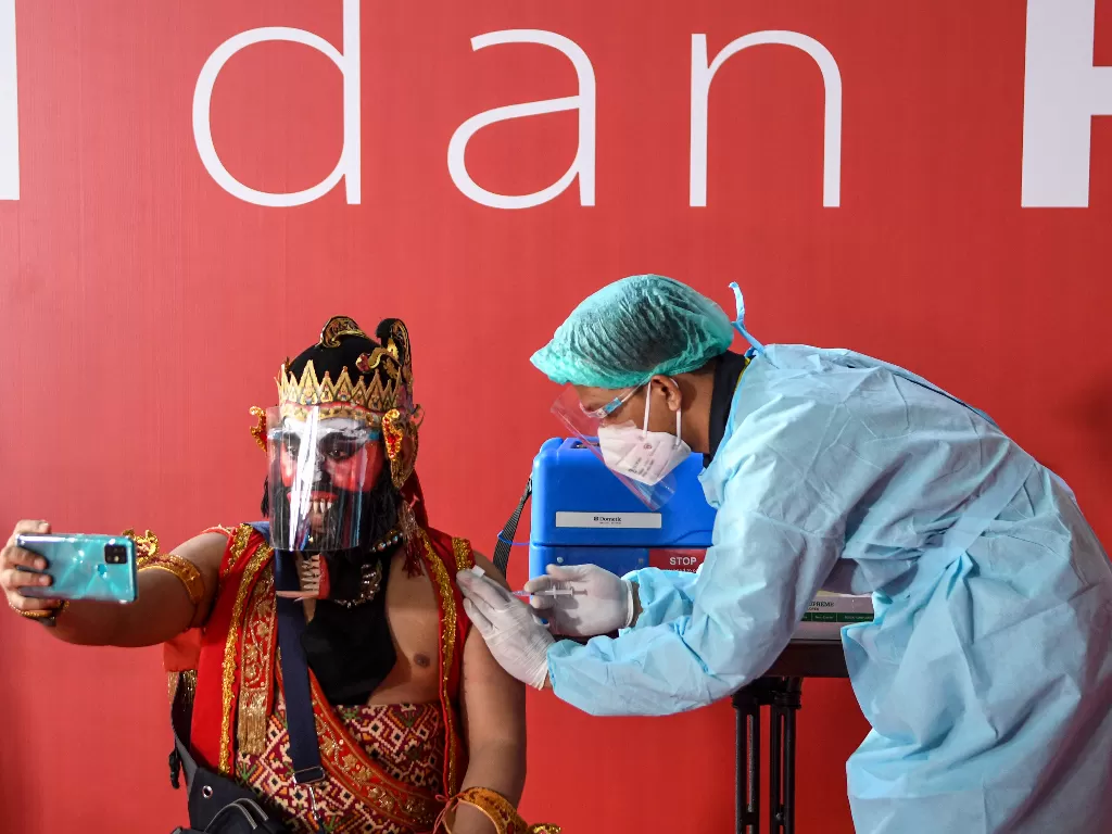 Seorang seniman dengan kostum pewayangan disuntik dosis pertama vaksin COVID-19 (ANTARA FOTO/M Risyal Hidayat)