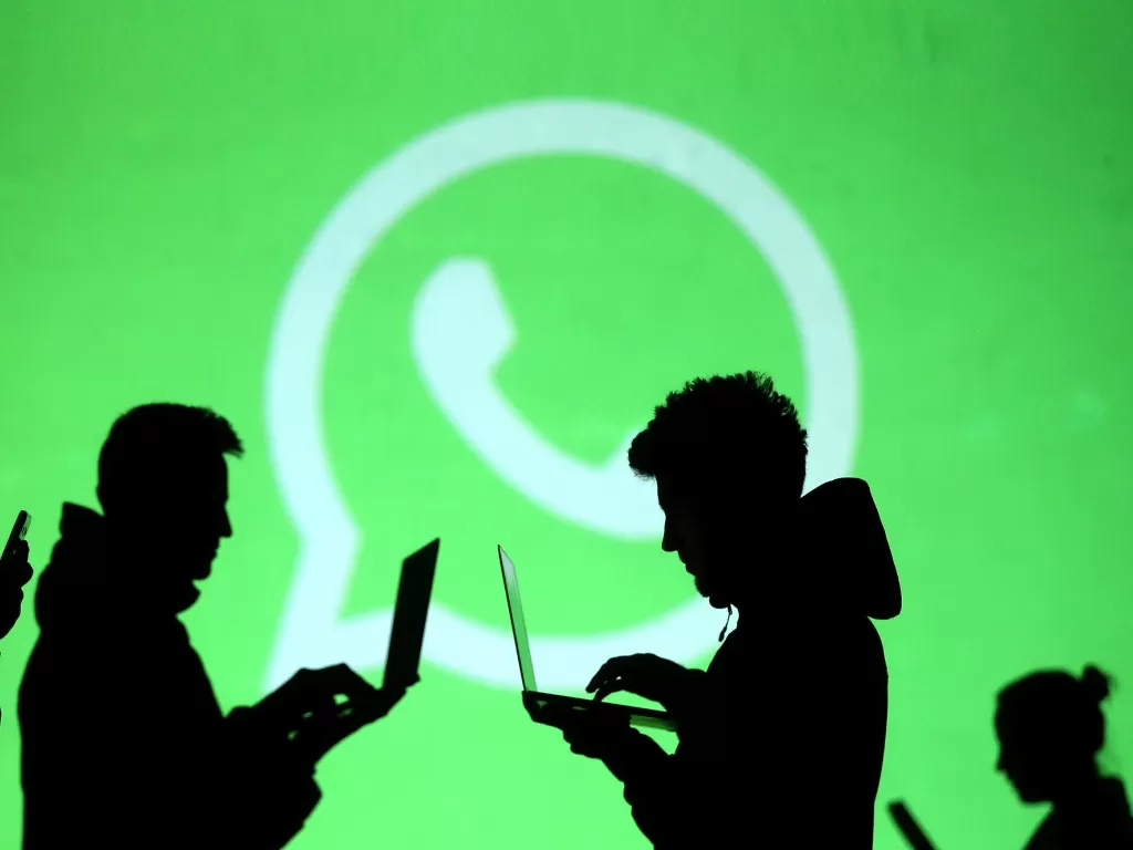 Ilustrasi beberapa orang sedang berdiri di depan logo WhatsApp (photo/REUTERS/Dado Ruvic)