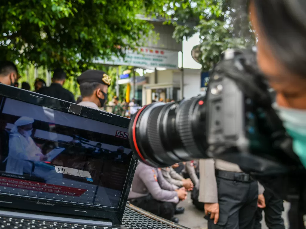 Pewarta foto mengambil gambar dari laptop yang menampilkan suasana sidang kasus pelanggaran protokol kesehatan dengan terdakwa Rizieq Shihab. (ANTARA FOTO/Galih Pradipta/foc.)