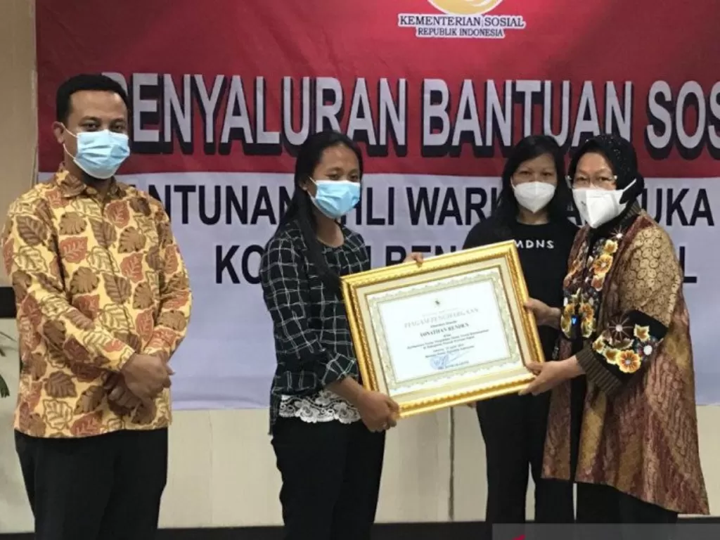 Menteri Sosial Tri Rismaharini menyerahkan penghargaan kepada dua guru yang menjadi korban meninggal dunia akibat penembakan oleh KKB di Papua di Makassar. (ANTARA/Devi Nindy)