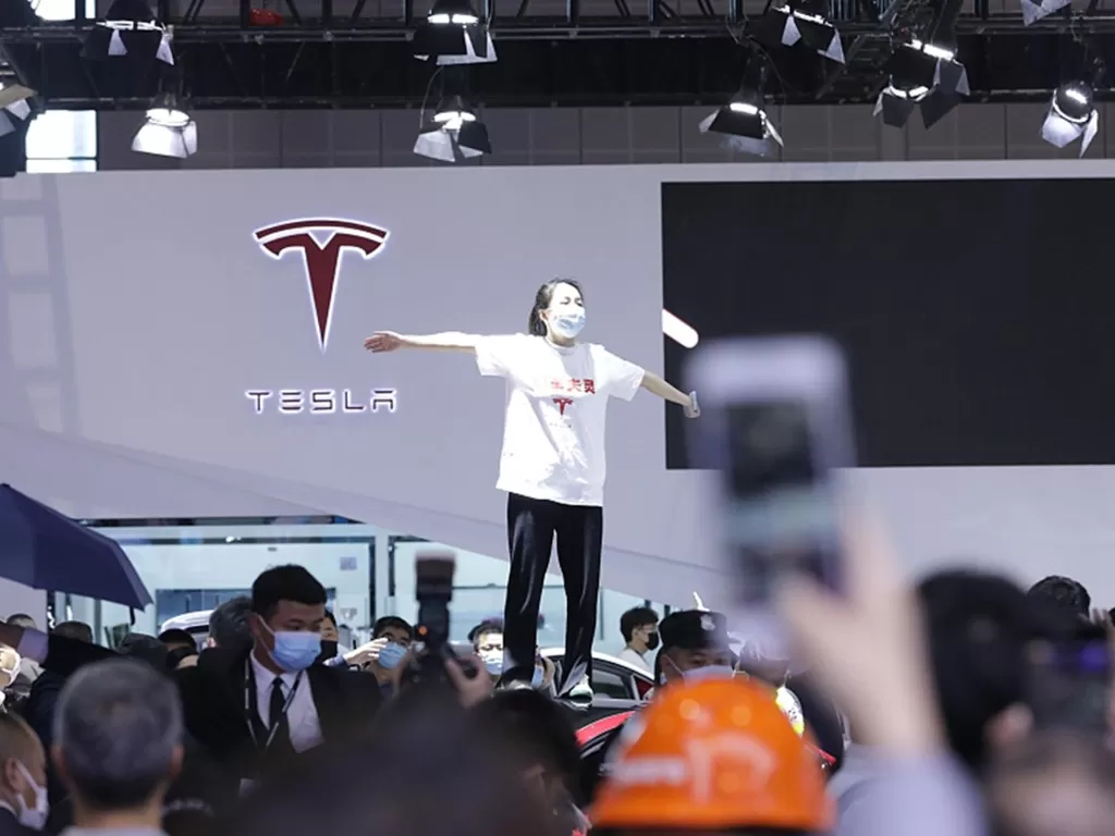 Wanita yang menaiki atap mobil Tesla di Shanghai Auto Show 2021 (photo/VCG via. GlobalTimes)