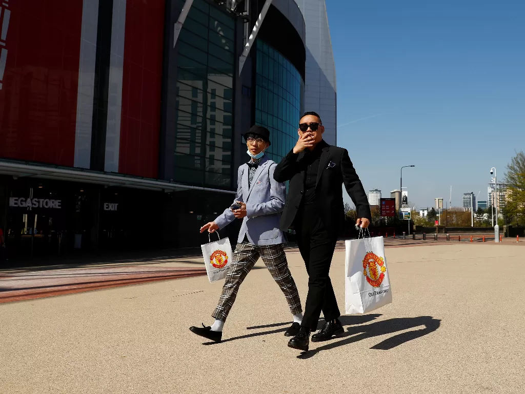 Dua orang yang membawa tas berlogo Manchester United di luar Old Trafford (REUTERS/Jason Cairnduff).