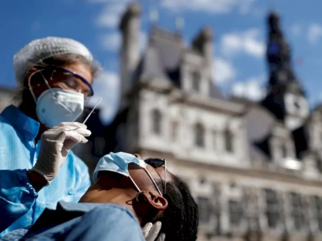 Seorang petugas kesehatan melakukan tes usap kepada seorang pasien di depan balai kota Paris, Prancis, (2/9/2020). (REUTERS/Christian Hartmann)