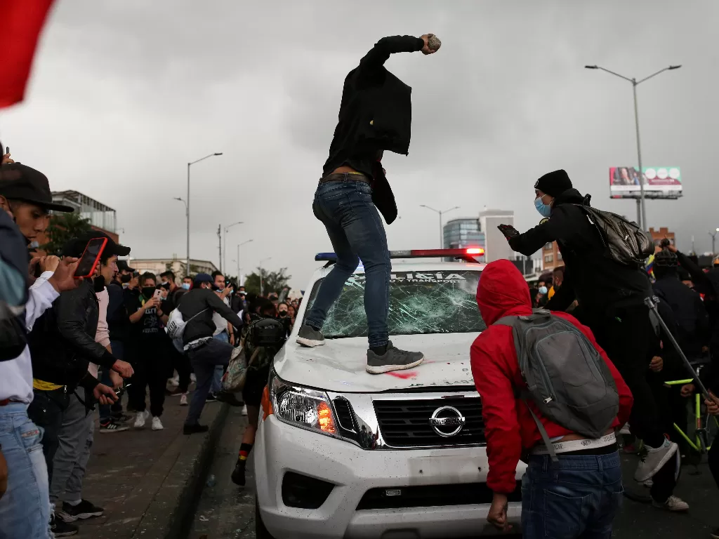 Seorang demonstran bersiap untuk melempar batu ke kendaraan polisi (REUTERS/Luisa Gonzalez)