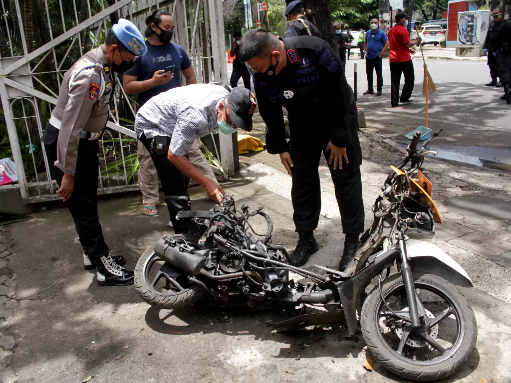 Polisi mengamati motor yang digunakan terduga pelaku bom bunuh diri sebelum dievakuasi di depan Gereja Katedral Makassar, Sulawesi Selatan, Senin (29/3/2021). (ANTARA/Arnas Padda)