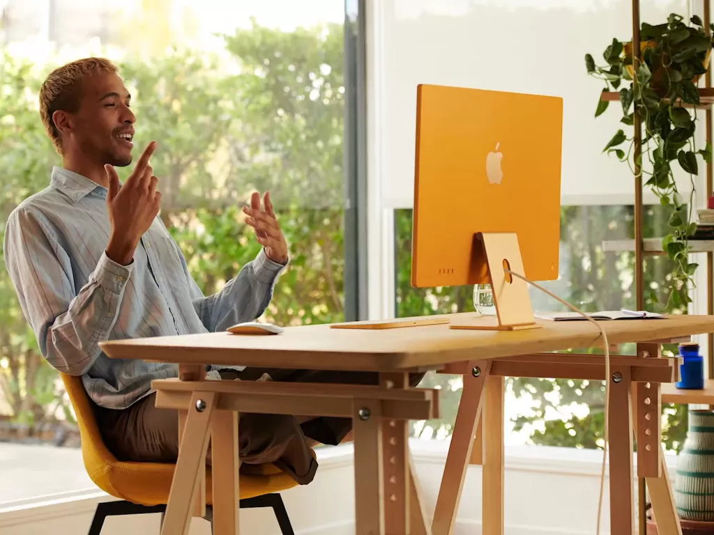 Seorang pria sedang berada di depan perangkat iMac 2021 terbaru (photo/Apple)