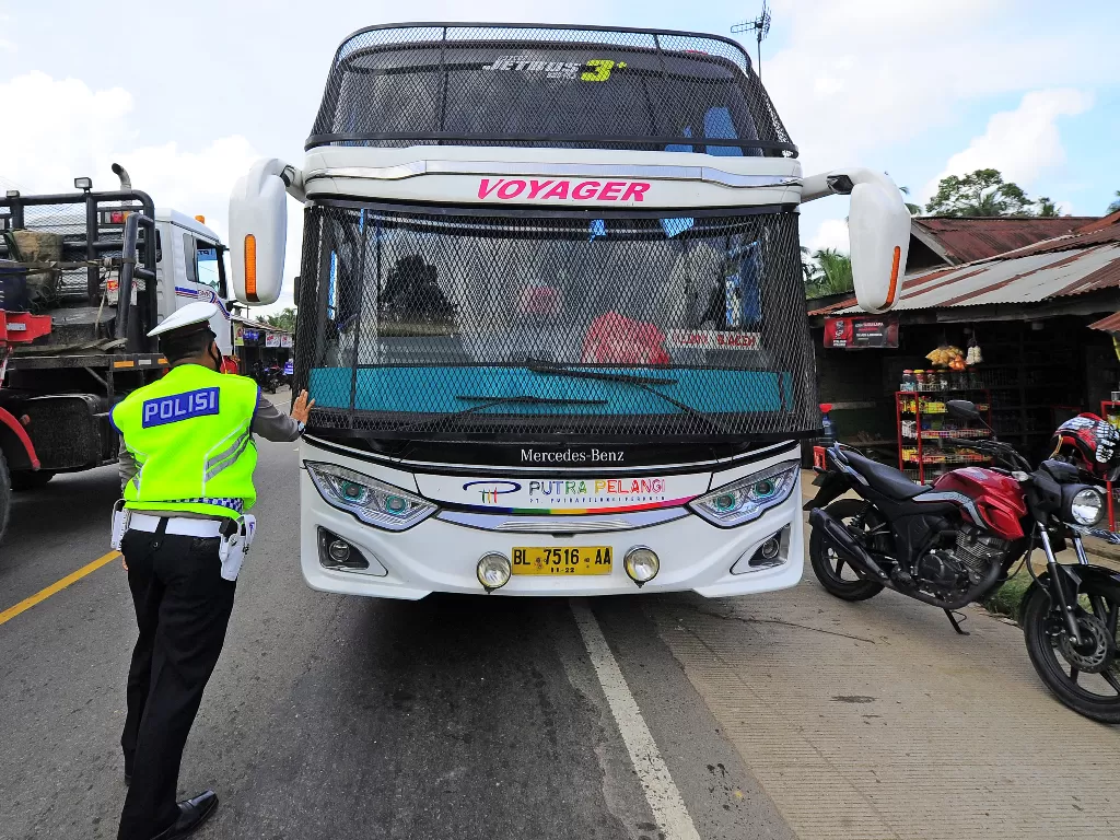 Petugas kepolisian menahan laju bus antarkota antarprovinsi (AKAP) rute Jakarta-Medan (ANTARA FOTO/Wahdi Septiawan)
