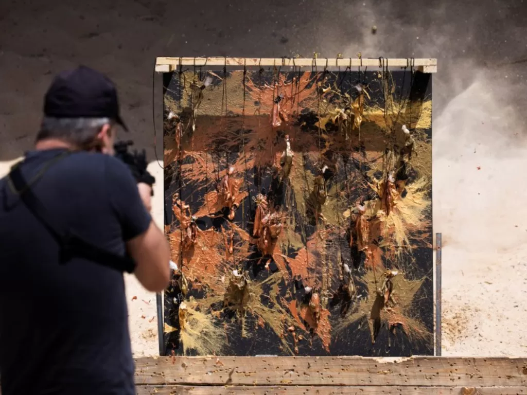 Mantan penembak jitu tentara Israel David Roytman, yang menggunakan lapangan tembak langsung sebagai studio dan senjata alih-alih kuas untuk membuat karya seninya, menggunakan pistol untuk menembak ke dalam kantong cat yang tergantung di antara moncong da