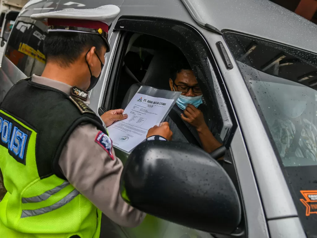 Petugas memeriksa dokumen pengendara di pos penyekatan mudik (ANTARA FOTO/Galih Pradipta)