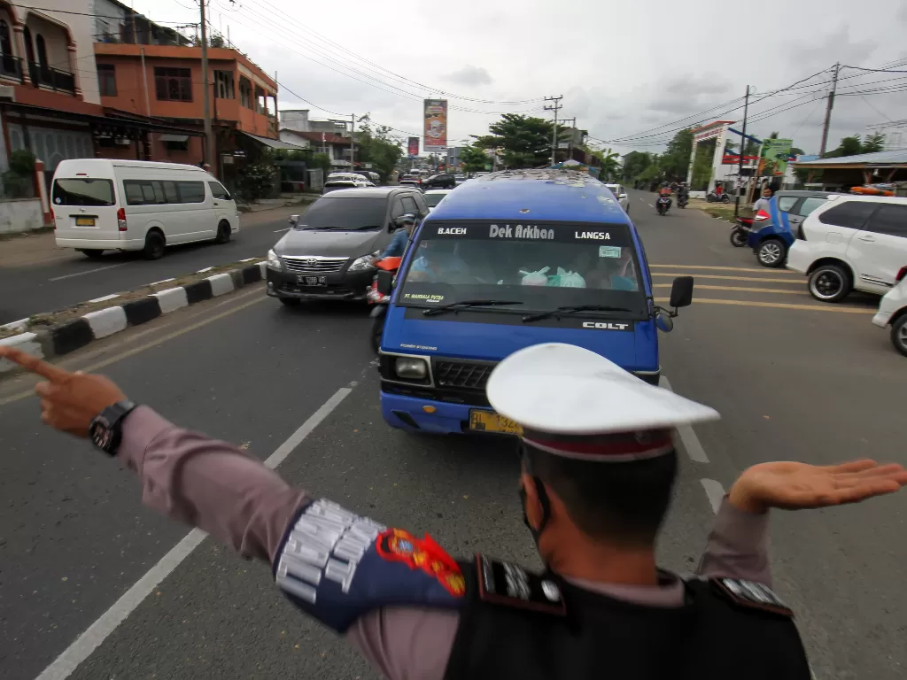 Petugas gabungan Operasi Ketupat Seulawah Polres Lhokseumawe mengarahkan mobil angkutan umum untuk putar balik di pos penyekatan mudik jalan lintas Aceh-Sumut, Lhokseumawe, Aceh, Kamis (6/5/2021). (ANTARA/Rahmad)