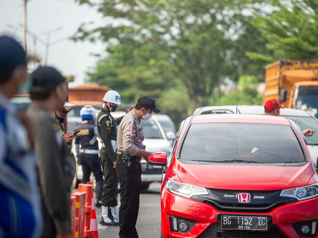 Petugas gabungan dari Polri, TNI, Dishub dan Sat Pol PP memeriksa kendaraan yang melintas di Jalan Lintas Timur Ogan Ilir (OI)-Palembang, Sumatera Selatan, Jumat (7/6/2021). (ANTARA FOTO/Nova Wahyudi)