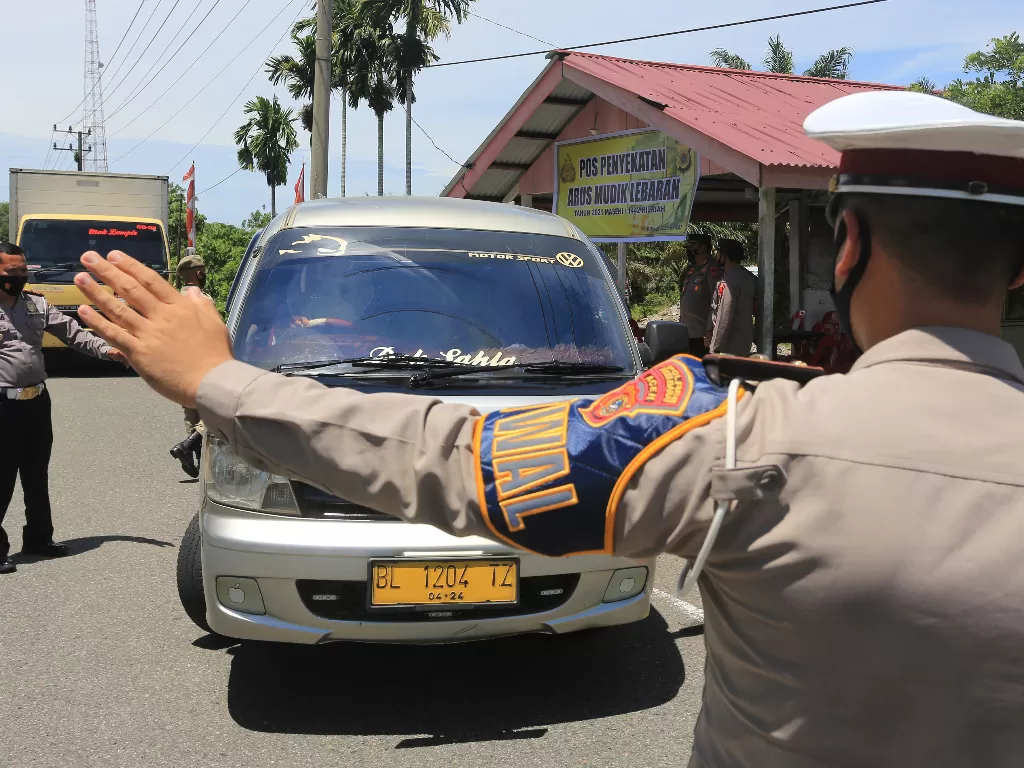 Petugas gabungan Operasi Ketupat Seulawah Polres Aceh Barat mengarahkan mobil angkutan umum untuk memutar balik di pos penyekatan mudik antar Kabupaten Aceh Barat dan Kabupaten Aceh Jaya, Aceh, Jumat (7/5/2021). (Syifa Yulinnas)