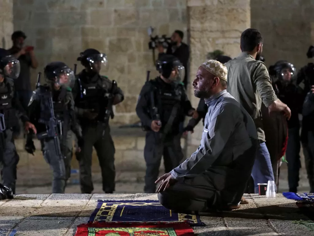 Seorang pria Palestina berdoa ketika polisi Israel berkumpul selama bentrokan di kompleks Masjid Al-Aqsa. (ANTARA FOTO/REUTERS/Ammar Awad)