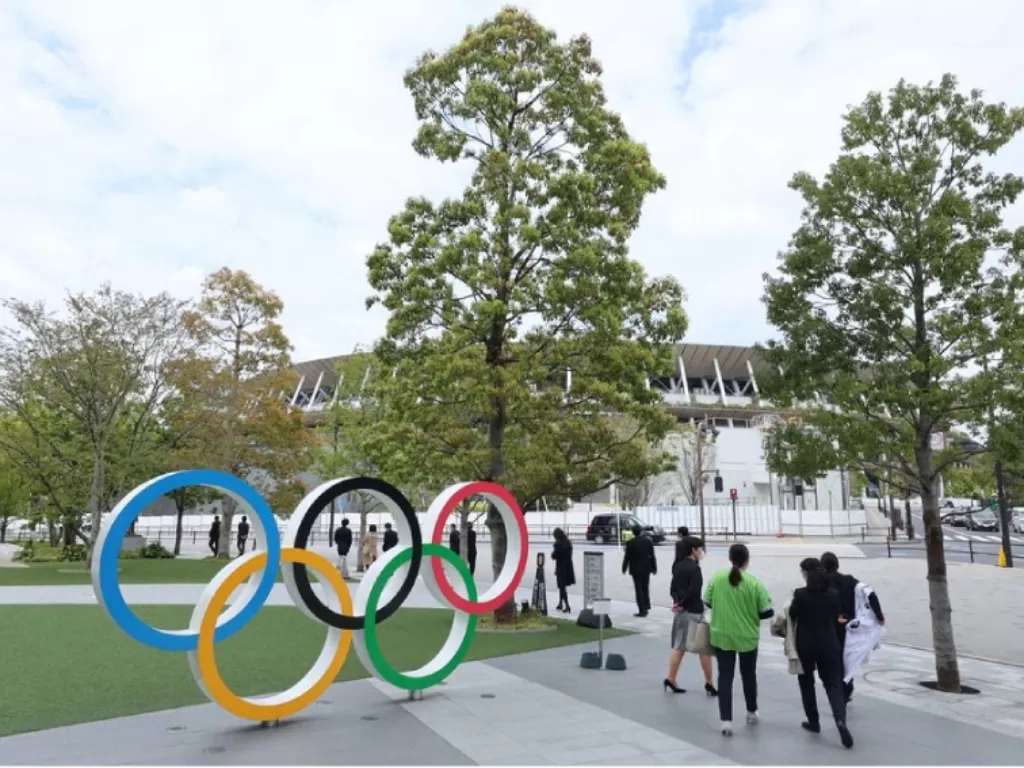 Orang-orang berjalan melewati patung cincin Olimpiade di dekat Stadion Nasional Jepang sebagai persiapan untuk Olimpiade Musim Panas Tokyo 2020 yang akan dimulai pada Juli 2021. (photo/Dok. Asia One via REUTERS)
