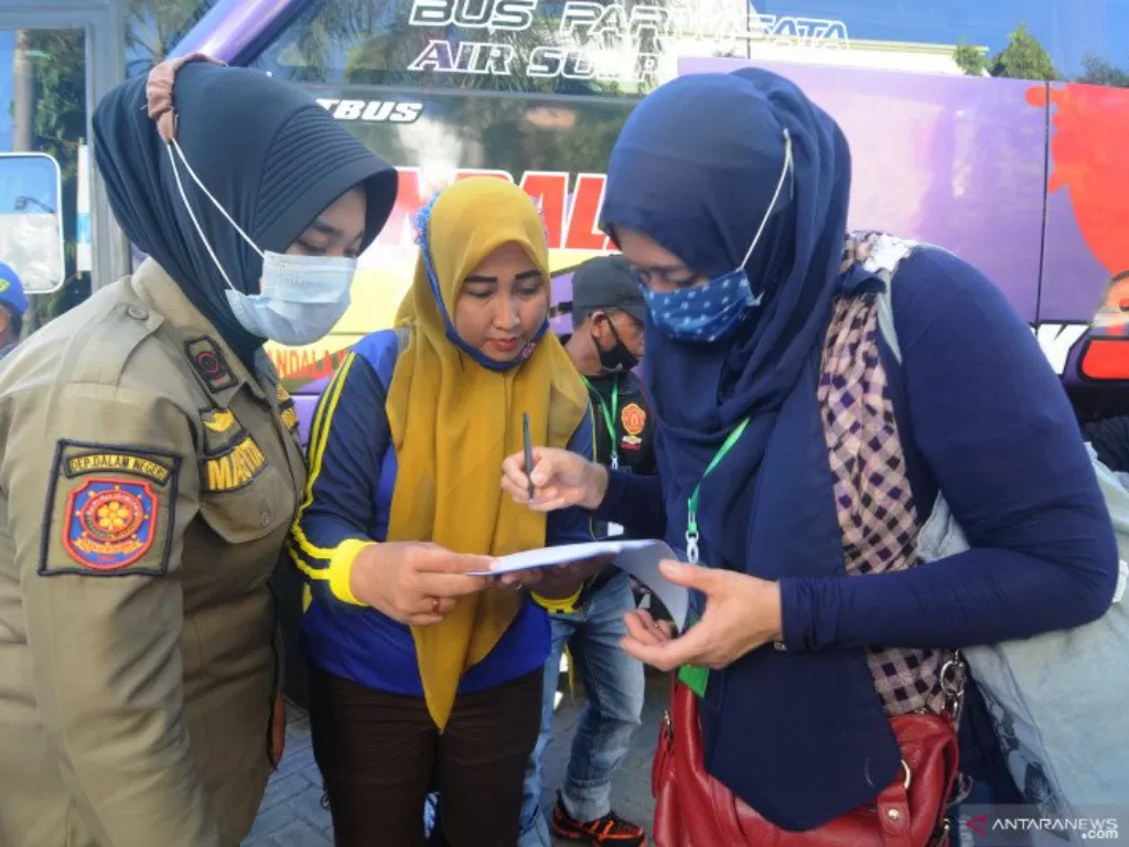 Petugas mendata pekerja migran Indonesia sebelum menjalani karantina di Islamic Center, Pamekasan, Jawa Timur, Senin (10-5-2021).  (photo/ANTARA FOTO/Saiful Bahri)