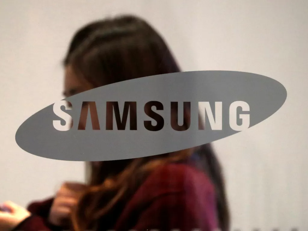 Seorang wanita sedang berada di belakang logo Samsung (photo/REUTERS/Kim Hong-Ji)
