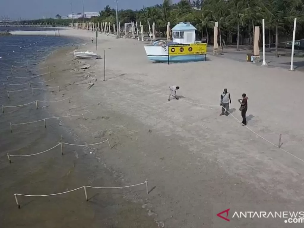 Petugas memasang tali pancang untuk membatasi area pantai dengan laut di kawasan Taman Impian Jaya Ancol, Jakarta Utara, Sabtu (15/5/2021). (photo/ANTARA/ HO-Taman Impian Jaya Ancol)