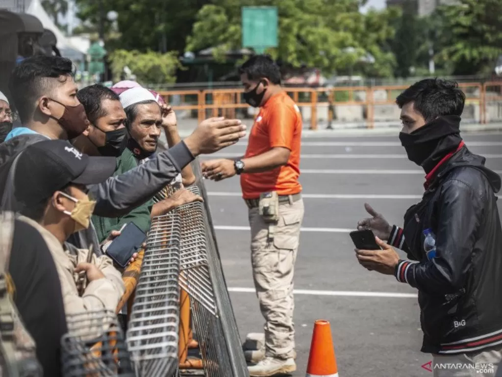 Petugas memberikan imbauan kepada warga yang akan berwisata untuk kembali pulang di depan pintu masuk Ancol Taman Impian, Jakarta. (Foto: ANTARA/Aprillio Akbar)