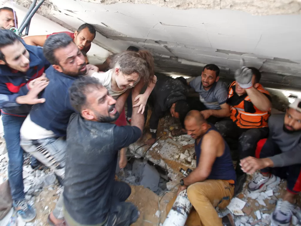   Tim penyelamat membawa seorang gadis saat mereka mencari korban di tengah puing-puing di lokasi serangan udara Israel, di Kota Gaza 16 Mei 2021. (photo/REUTERS/Mohammed Salem)