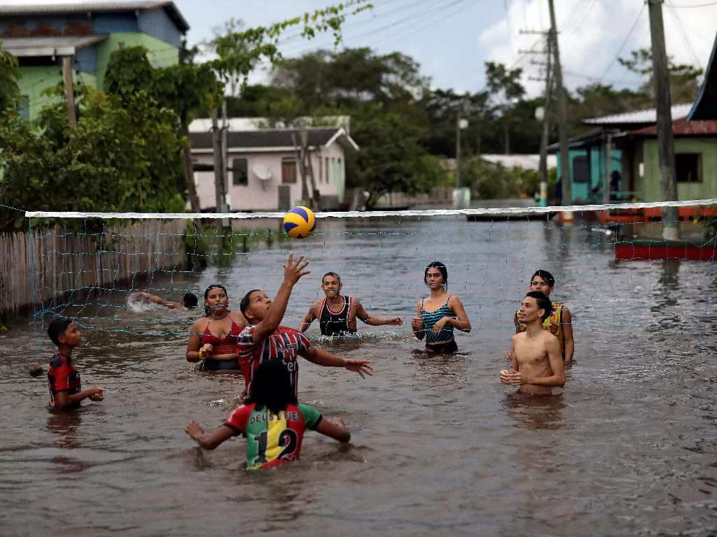 Warga bermain bola voli di jalanan yang terendam banjir (REUTERS/Bruno Kelly)