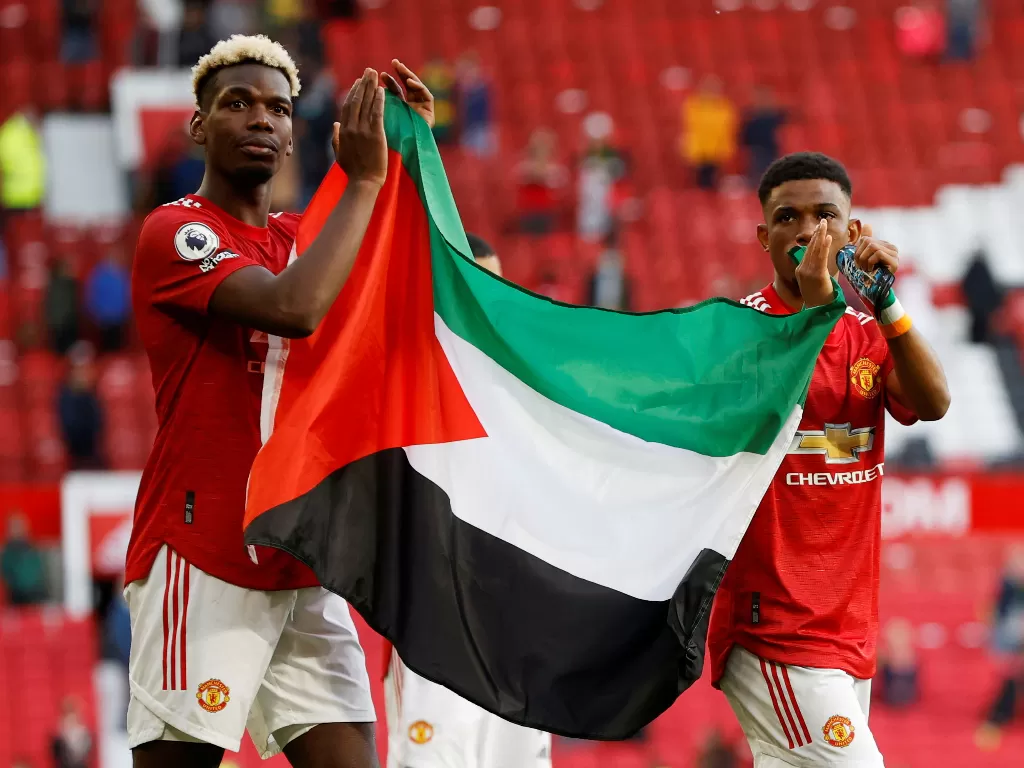 Paul Pogba dan Amad Diallo bentangkan bendera Palestina di Old Trafford, Rabu (19/5/2021). (REUTERS/PHIL NOBLE)