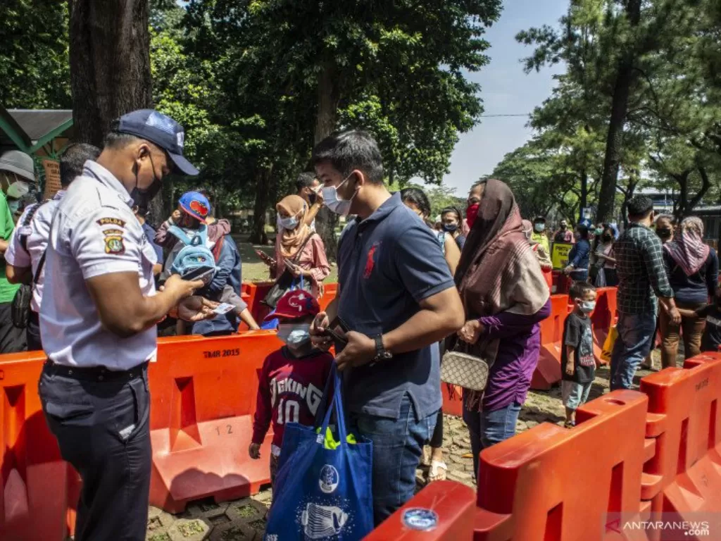 Petugas memeriksa identitas diri wisatawan sebelum memasuki kawasan Taman Margasatwa Ragunan di Jakarta, Kamis (14/5/2021). (ANTARA FOTO/Aprillio Akbarfoc)