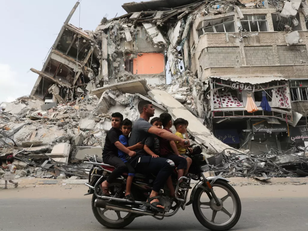Ilustrasi. Warga Palestina mengendarai sepeda motor melewati lokasi serangan udara Israel, setelah gencatan senjata Israel-Hamas, di Gaza 21 Mei 2021. (photo/REUTERS/Suhaib Salem)