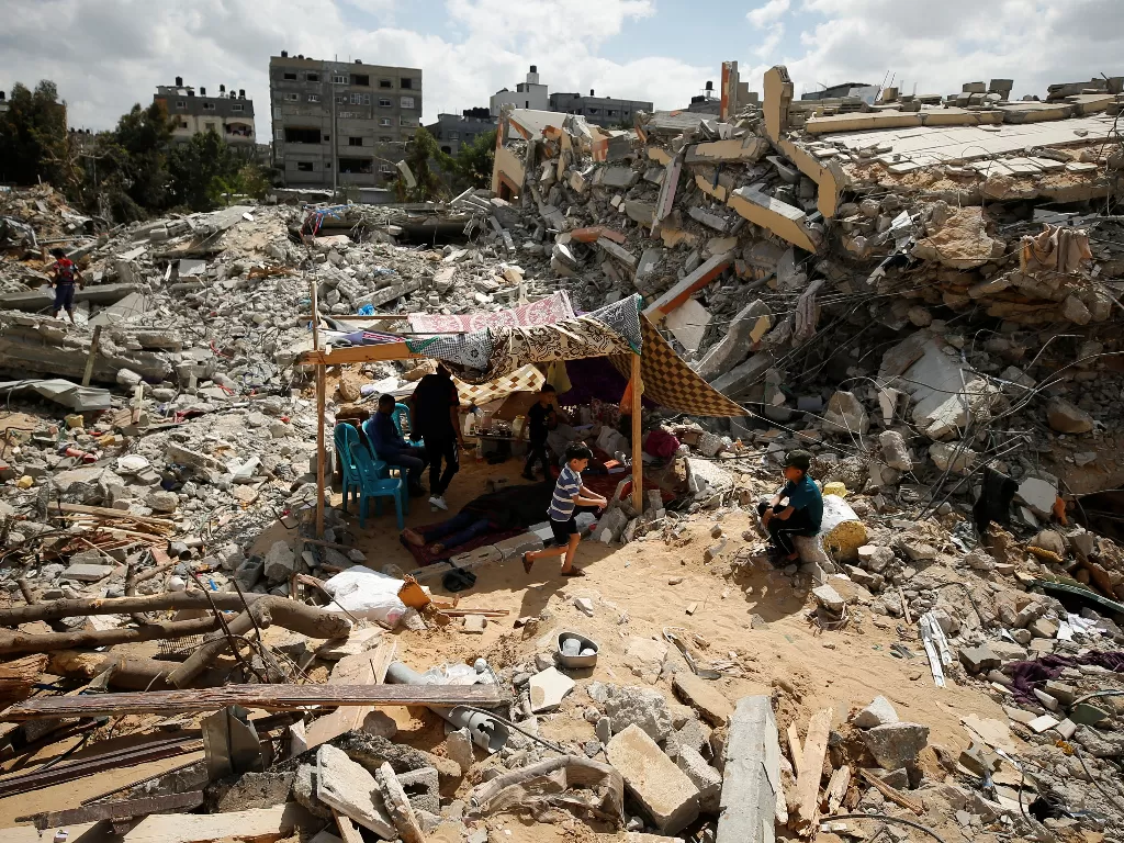  Warga Palestina duduk di tenda darurat di tengah puing-puing rumah mereka yang dihancurkan oleh serangan udara Israel selama pertempuran Israel-Hamas di Gaza 23 Mei 2021. (photo/REUTERS/Mohammed Salem)
