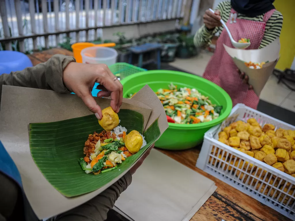 Pekerja memasak untuk kebutuhan gerakan nasi bungkus dua ribu (ANTARA FOTO/Raisan Al Farisi)