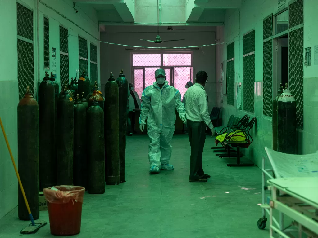 Seorang petugas kesehatan berjalan melewati tabung oksigen di luar unit perawatan intensif COVID-19, India, 11 Mei 2021. (photo/REUTERS/Denmark Siddiqui)