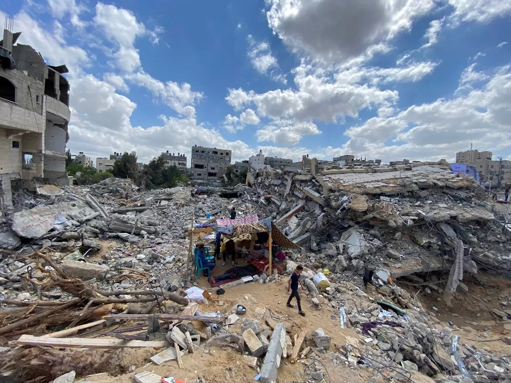 Seorang bocah Palestina berjalan di dekat tenda darurat mereka di tengah puing-puing rumah mereka yang dihancurkan oleh serangan udara Israel selama pertempuran Israel-Palestina di Gaza 23 Mei 2021. (photo/REUTERS/Mohammed Salem)