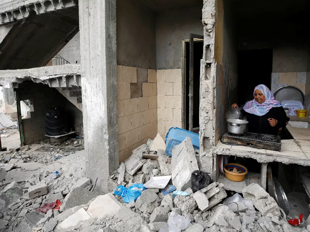 Korban serangan Israel di Palestina memasak di rumahnya yang hancur. (REUTERS/Mohammed Salem)