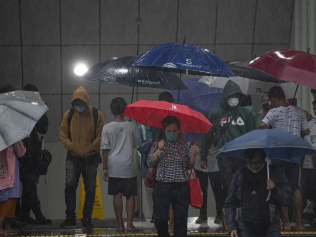 Warga menggunakan payung saat hujan mengguyur Stasiun MRT Dukuh Atas BNI, Jakarta, Kamis (13/8/2020). (ANTARA/Aditya Pradana Putra)
