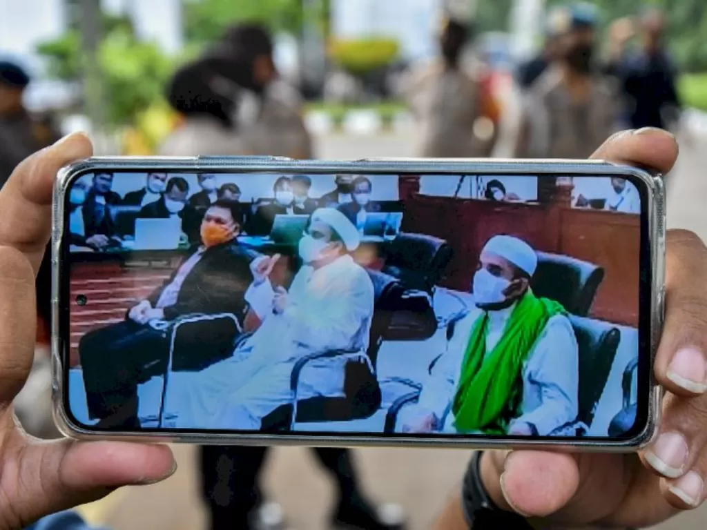 Layar telepon pintar menampilkan suasana sidang Habib Rizieq Shihab (tengah) di Pengadilan Negeri Jakarta Timur, Kamis (27/5/2021). (ANTARA/Fakhri Hermansyah)