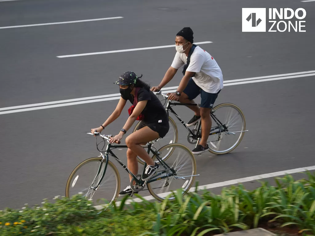 Warga mengenakan masker dan face shield saat bersepeda di kawasan Bundaran HI, Jakarta, Minggu (14/6/2020). (INDOZONE)