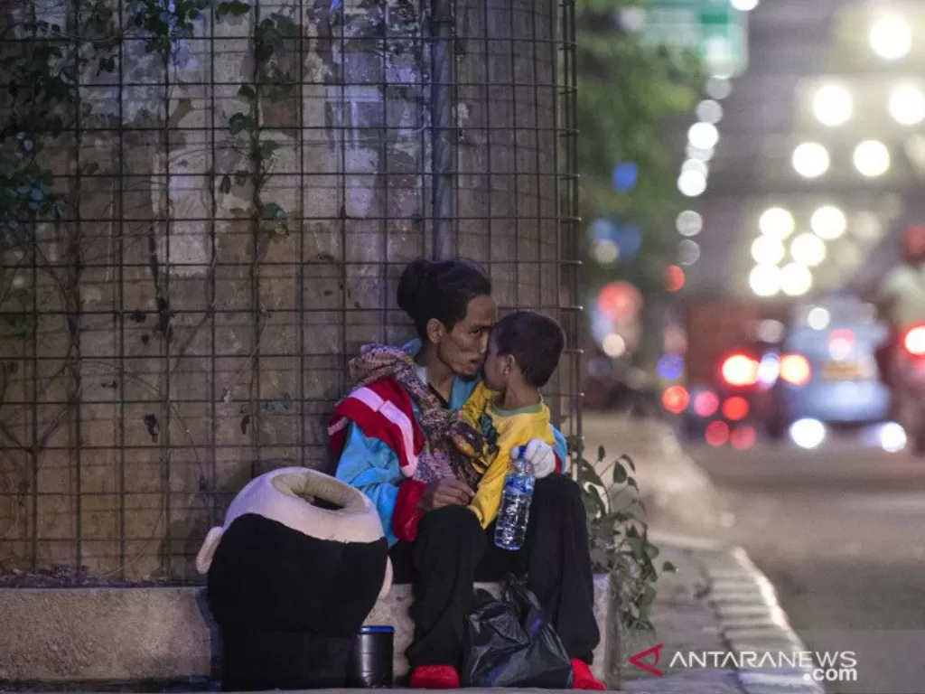 Seorang pria mencium anaknya saat beristirahat disela mengamen sebagai badut di Jalan Pangeran Antasari, Jakarta Selatan, Sabtu (19/12/2020). (photo.ANTARA FOTO/Sigid Kurniawan/ilustrasi)