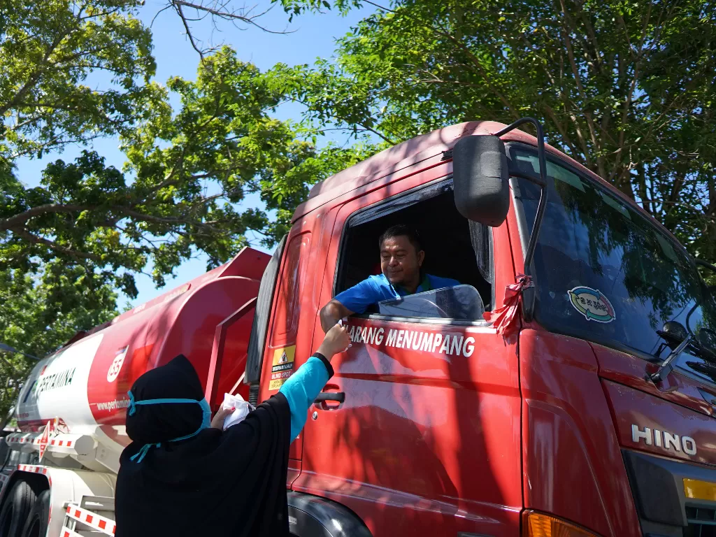 Petugas Kelurahan memberikan masker kepada seorang pengemudi truk tanki BBM (ANTARA FOTO/Adiwinata Solihin)