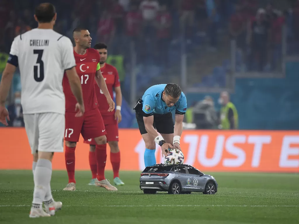Wasit mengambil bola yang diantar mobil remot kontrol di laga pembuka EURO 2020. (photo/REUTERS/ALBERTO LINGRIA)