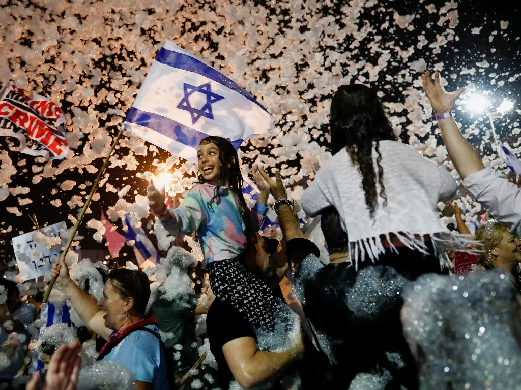 Orang-orang merayakan setelah parlemen Israel memberikan suara dalam pemerintahan koalisi baru, mengakhiri 12 tahun kekuasaan Benjamin Netanyahu (REUTERS/Corinna Kern)