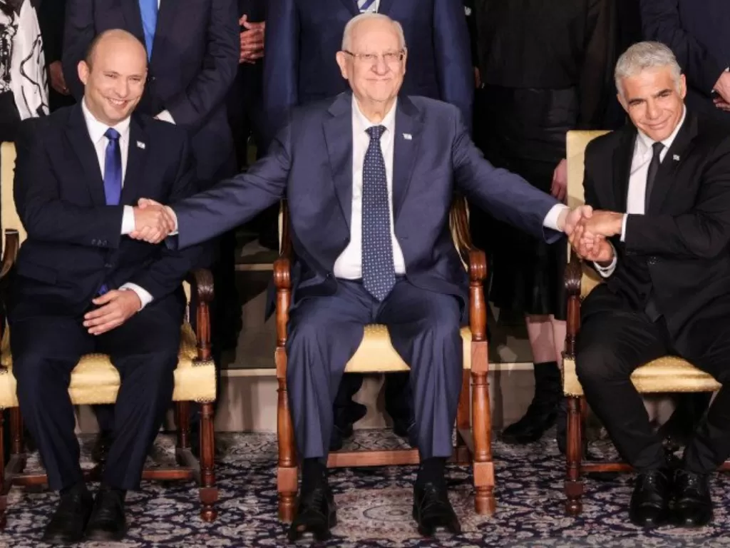 Presiden Israel Reuven Rivlin berada diantara Perdana Menteri Naftali Bennett dan Menteri Luar Negeri Yair Lapid saat berfoto bersama para menteri pemerintahan baru Israel, di Yerusalem, Senin (14/6/2021). (REUTERS/Ronen Zvulun).
