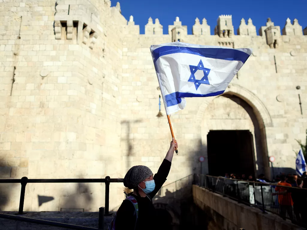 Seorang wanita Israel memegang bendera di dekat gerbang Damaskus di luar Kota Tua Yerusalem 15 Juni 2021. (photo/REUTERS/Ronen Zvulun/File Foto)