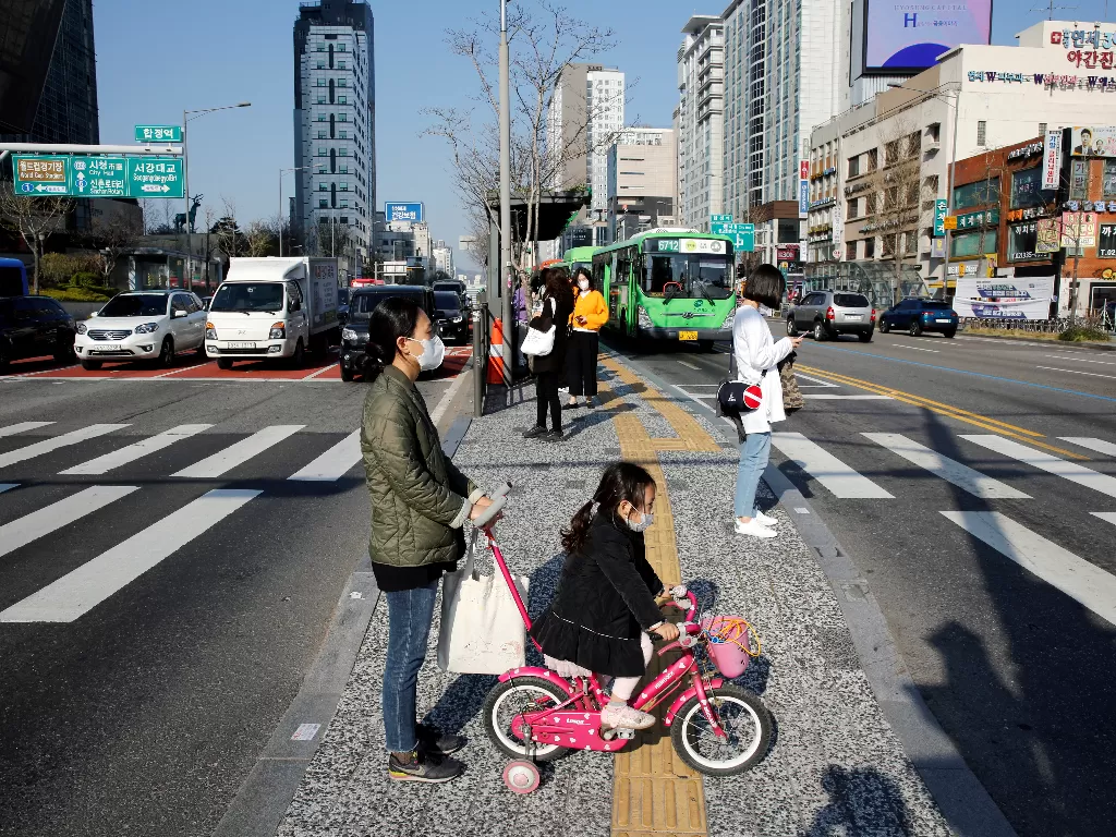 Ilustrasi. Seorang ibu dan anaknya mengenakan masker pelindung wajah, di tengah pandemi COVID-19, menunggu sinyal di zebra cross di pusat kota Seoul, Korea Selatan, 3 April 2020. (photo/REUTERS/Heo Ran)