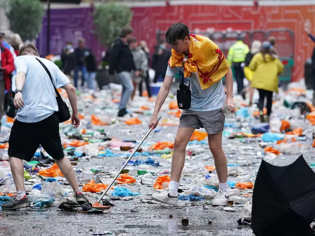 Fans skotlandia membersihkan sampah setelah pertandingan. (Photo/The Guardian)
