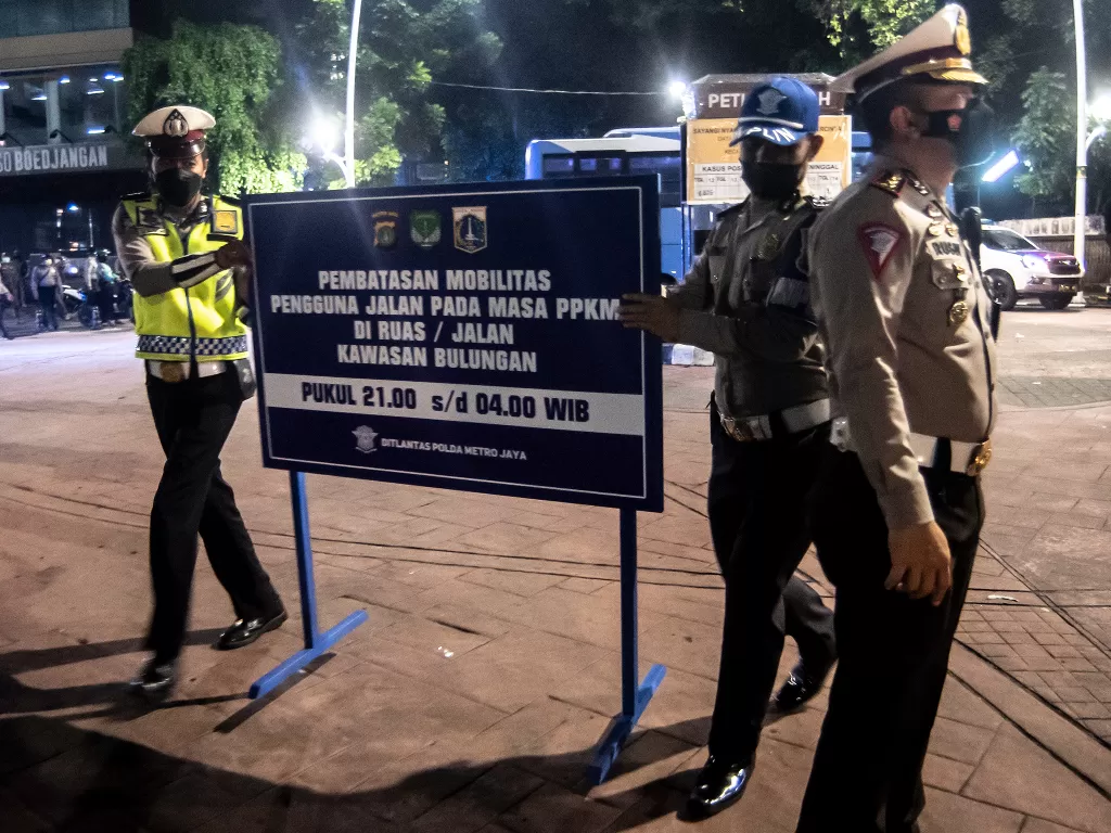  Petugas kepolisian meletakkan papan informasi saat melakukan penutupan jalan dalam rangka pembatasan mobilitas warga (ANTARA FOTO/Muhammad Adimaja/wsj.